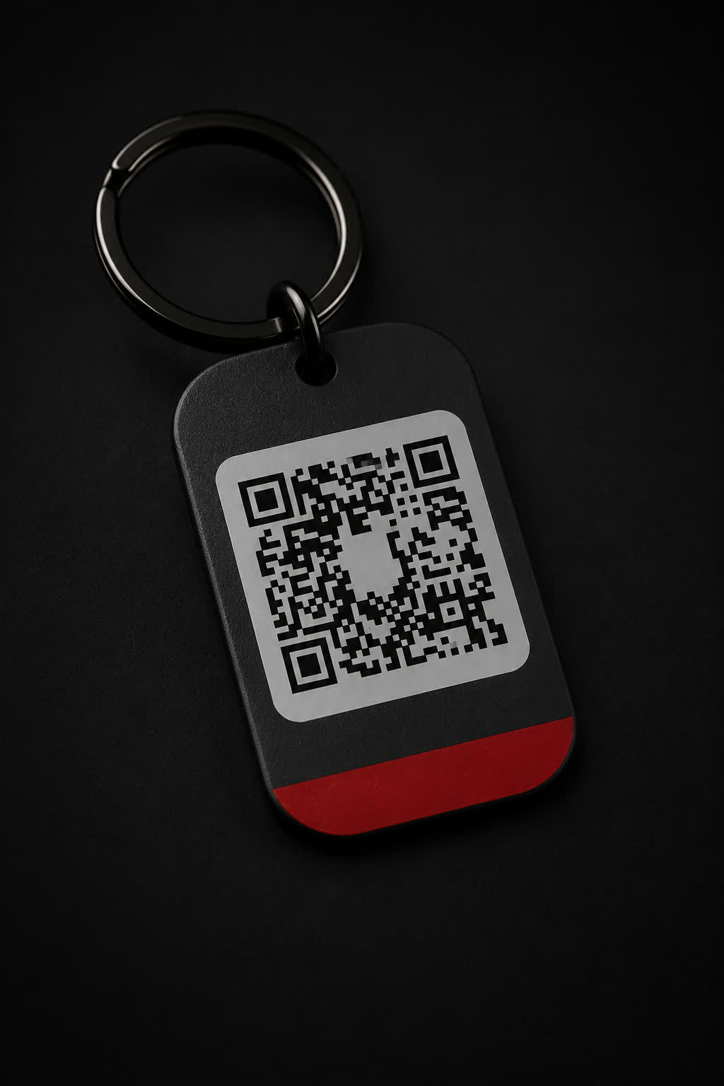 Llavero rectangular oscuro con el código QR grabado y un canto rojo.